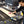Load image into Gallery viewer, A person uses the 2024 ROUTEK™ CNC Industrial Router Machine Pkg to cut wood, holding a pink measuring tape on a wooden plank. The machine, by Hytek Tools, features precision rails and includes a visible control pad.