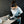 Load image into Gallery viewer, Wearing safety goggles and gloves, a person skillfully uses a handheld power tool to cut metal on a table. Nearby, the WeldTEK™ RAYCUS Fiber Laser Welder 1000-3000w by Hytek Tools hints at cutting-edge technology against a dark brick wall backdrop.