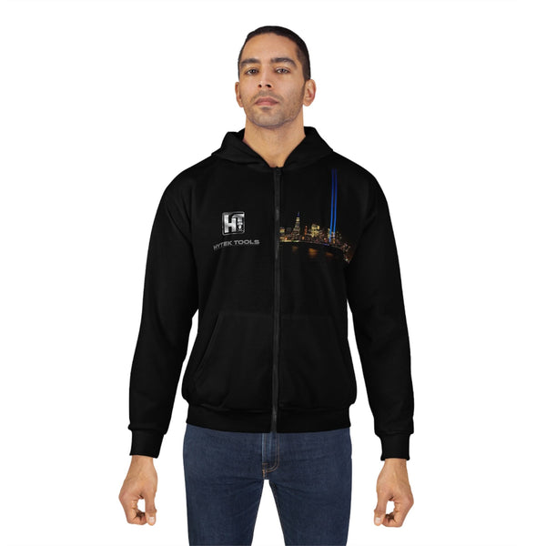 A man wearing a custom Hytek Tools NYC Unisex Zip Hoodie by Printify, featuring a cityscape design and the HTEK TOOLS logo on the left chest, styled with blue jeans against a plain white background.