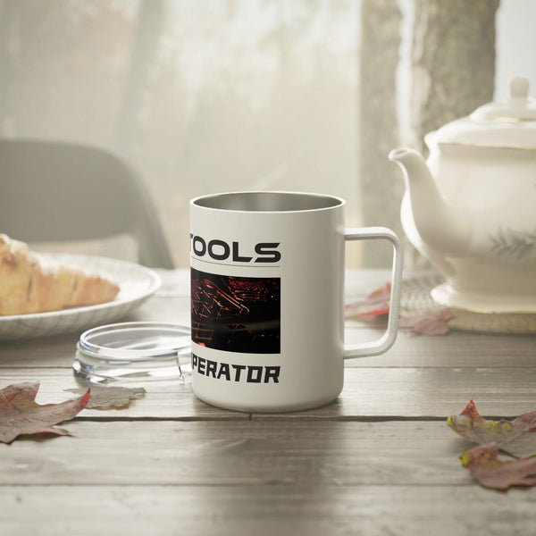A Printify Insulated Coffee Mug, 10oz, with design elements and text sits on a wood table near a teapot, pastry, and travel mug. Autumn leaves are scattered around with a blurred outdoor background visible through the window.